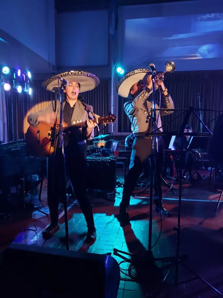 El dúo Experiencia Guadalupe en el escenario de un evento, con luces azules