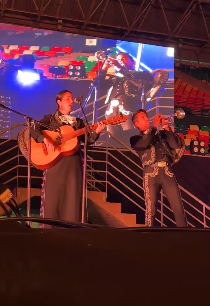 Los mariachis en el escenario de un evento, frente a una pantalla gigante