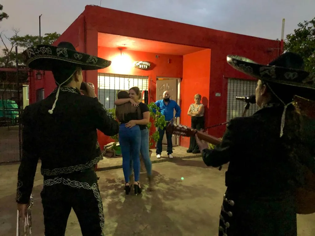 Serenata de noche frente a una casa: una pareja se abraza mientras los mariachis tocan