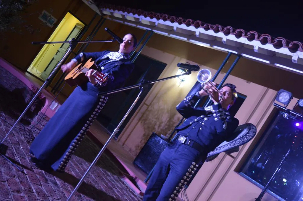 Los dos mariachis tocan de noche en la terraza de una casa iluminada